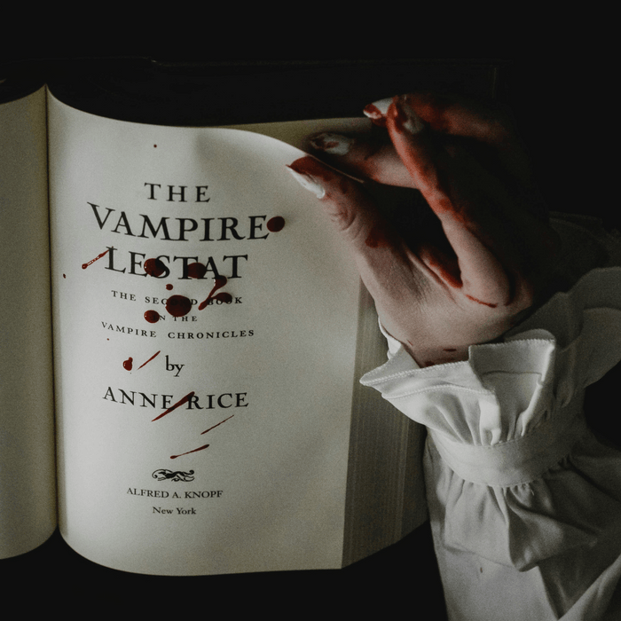 Moody Halloween aesthetic with a blood-stained hand holding Anne Rice’s The Vampire Lestat, a gothic horror classic from The Vampire Chronicles series.