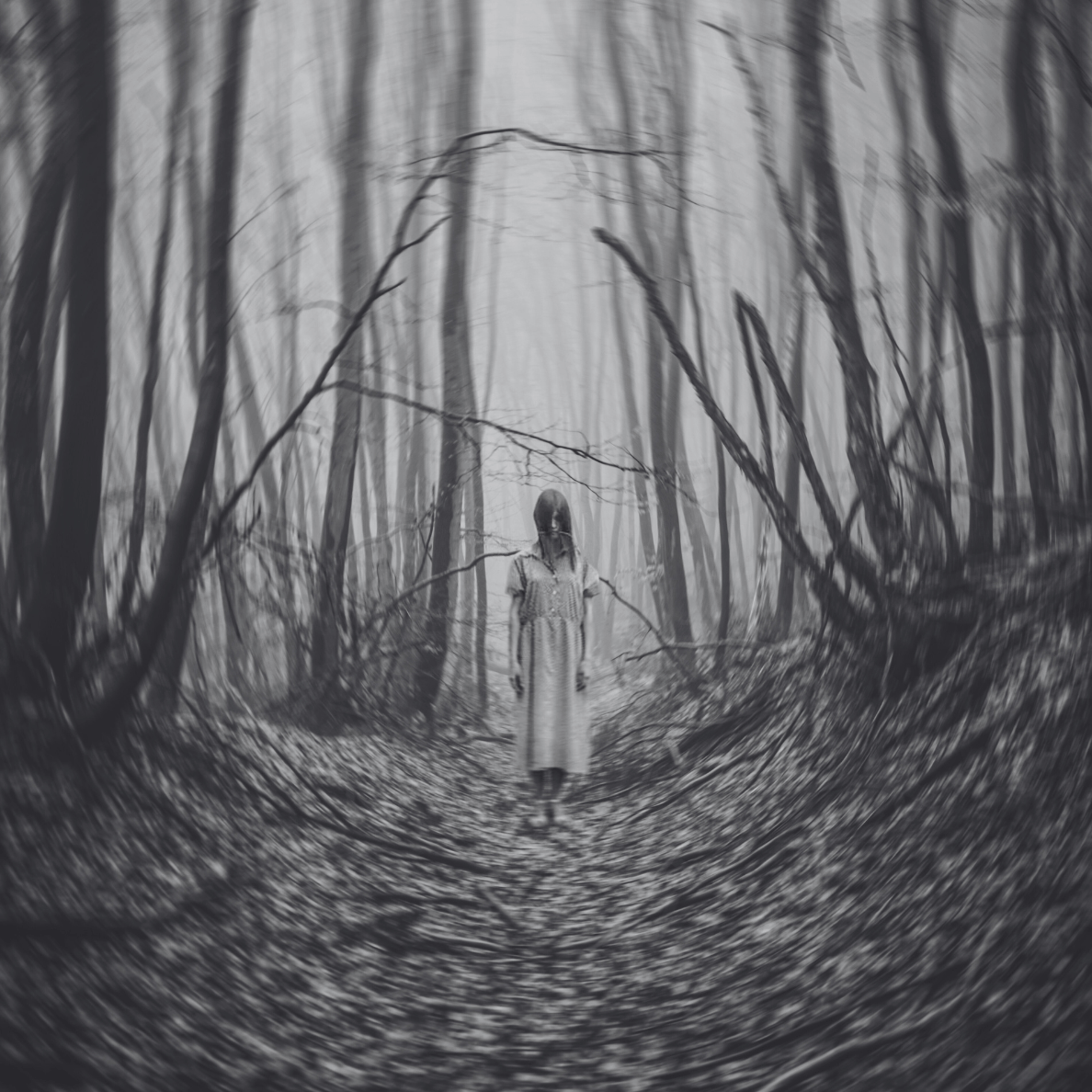 Eerie black-and-white image of a girl in a white dress standing motionless in a foggy, twisted forest path, creating a chilling horror atmosphere for scary books.