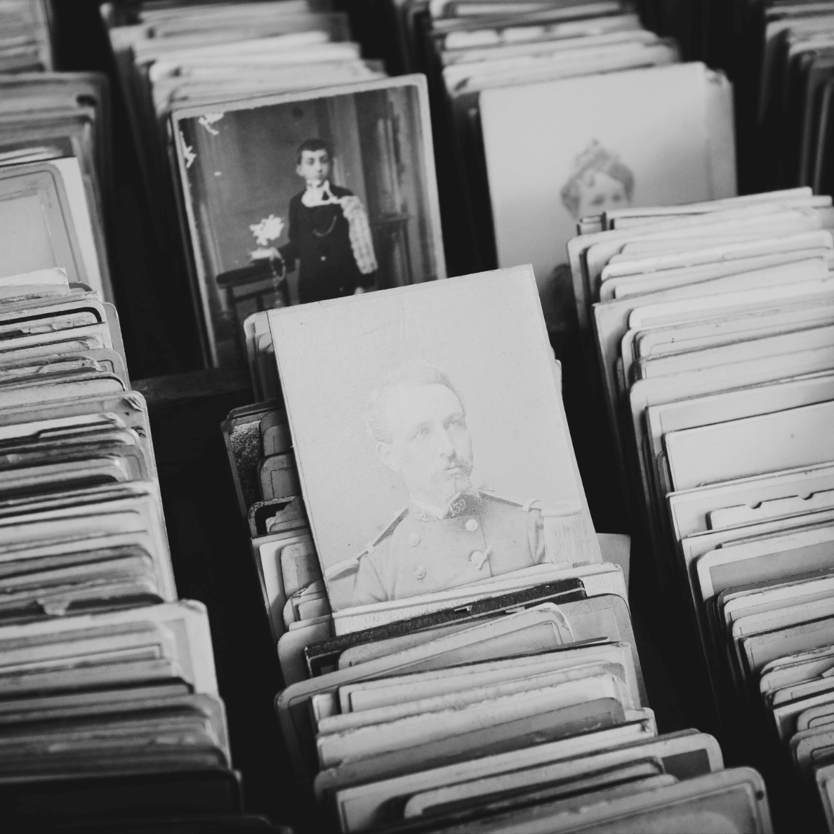 Vintage black-and-white photograph of old portrait cards neatly arranged in stacks, symbolizing history, biographies, and nonfiction books for curious minds.