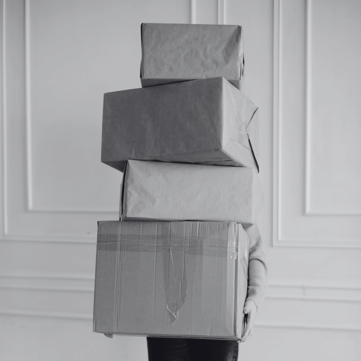 Stack of gray gift boxes against a white paneled wall