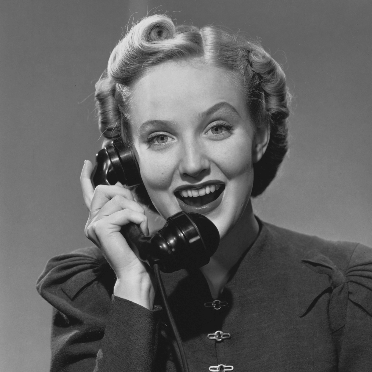 Vintage black and white photo of a woman talking on a rotary phone