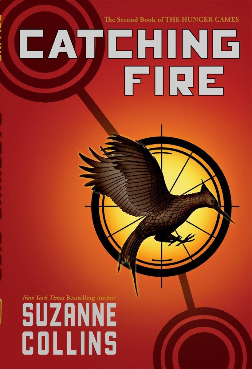 Book cover of 'Catching Fire' by Suzanne Collins with a bird and target design on an orange background.