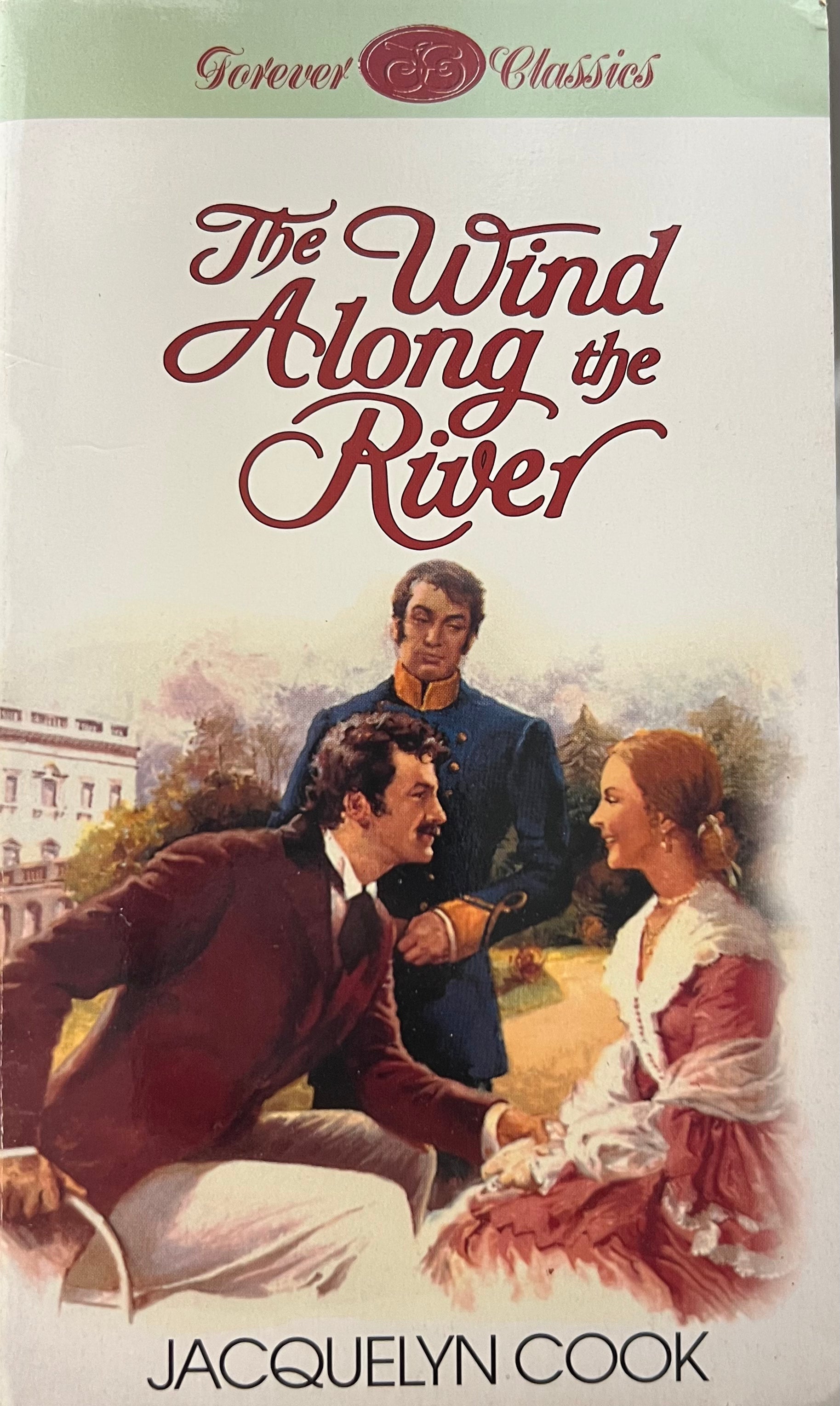 Book cover of 'The Wind Along the River' by Jacquelyn Cook featuring a scene with three people outdoors.