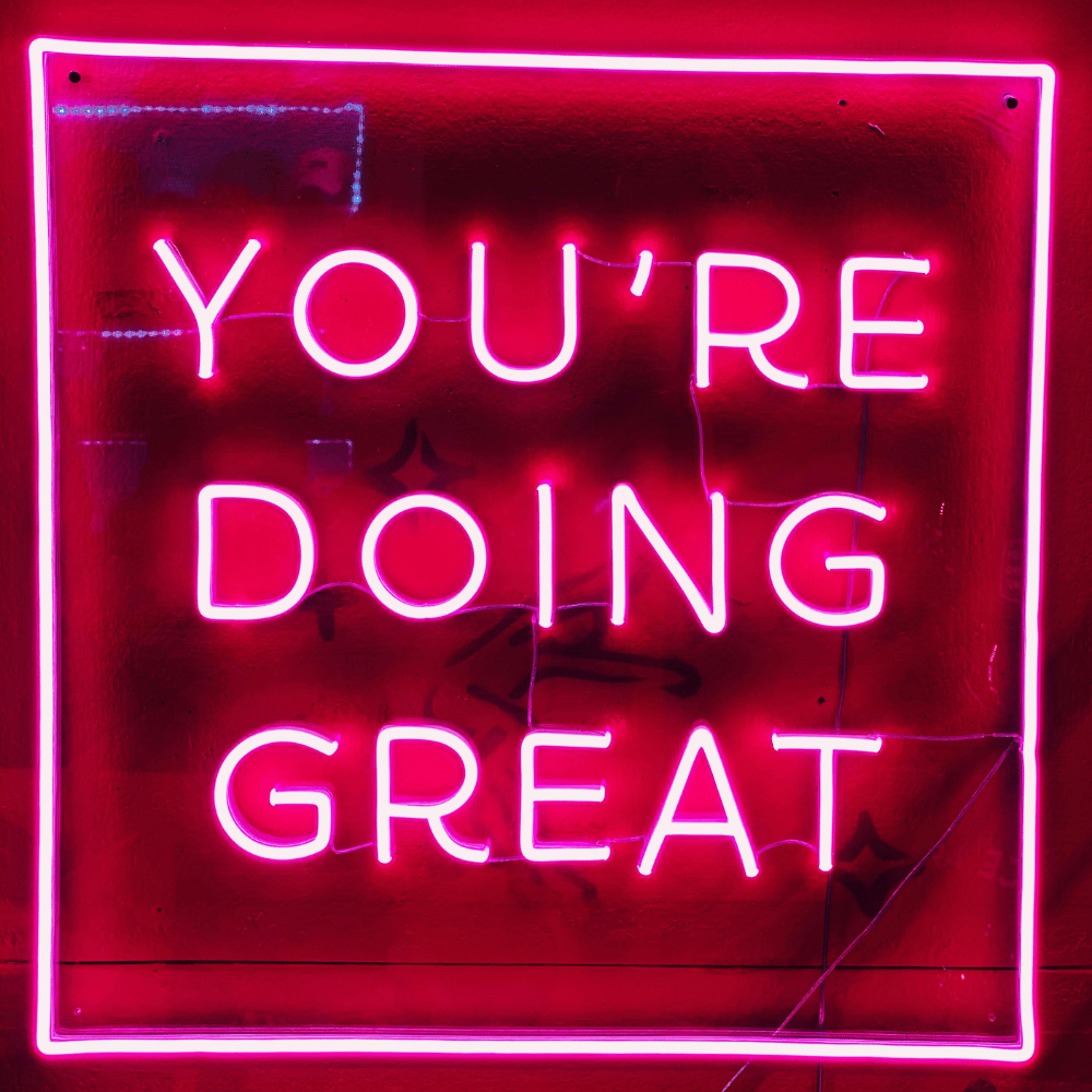 Neon sign with 'YOU'RE DOING GREAT' text on a red background
