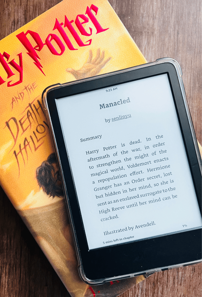 An e-reader displaying the fanfiction “Manacled” by SenLinYu, resting on a hardcover copy of “Harry Potter and the Deathly Hallows” by J.K. Rowling on a wooden surface.
