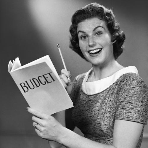Smiling vintage woman holding a pencil and an open book labeled “BUDGET,” symbolizing affordable, budget-friendly books for thrifty readers.