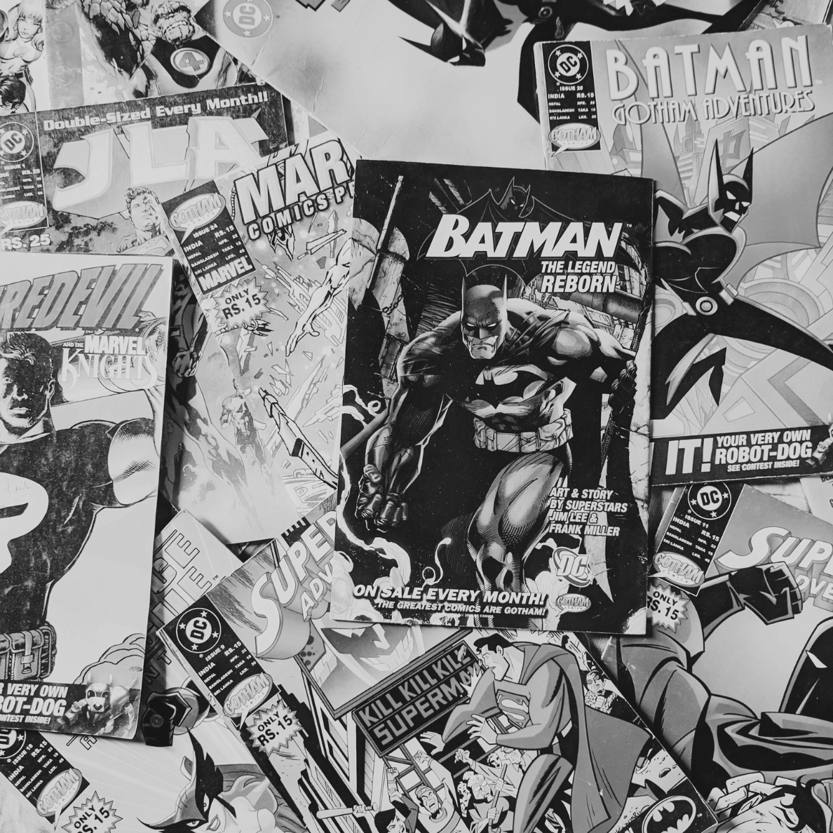 Black-and-white photo of a scattered collection of comic books featuring Batman, Superman, Daredevil, and Marvel covers, symbolizing manga, comics, and graphic novels.