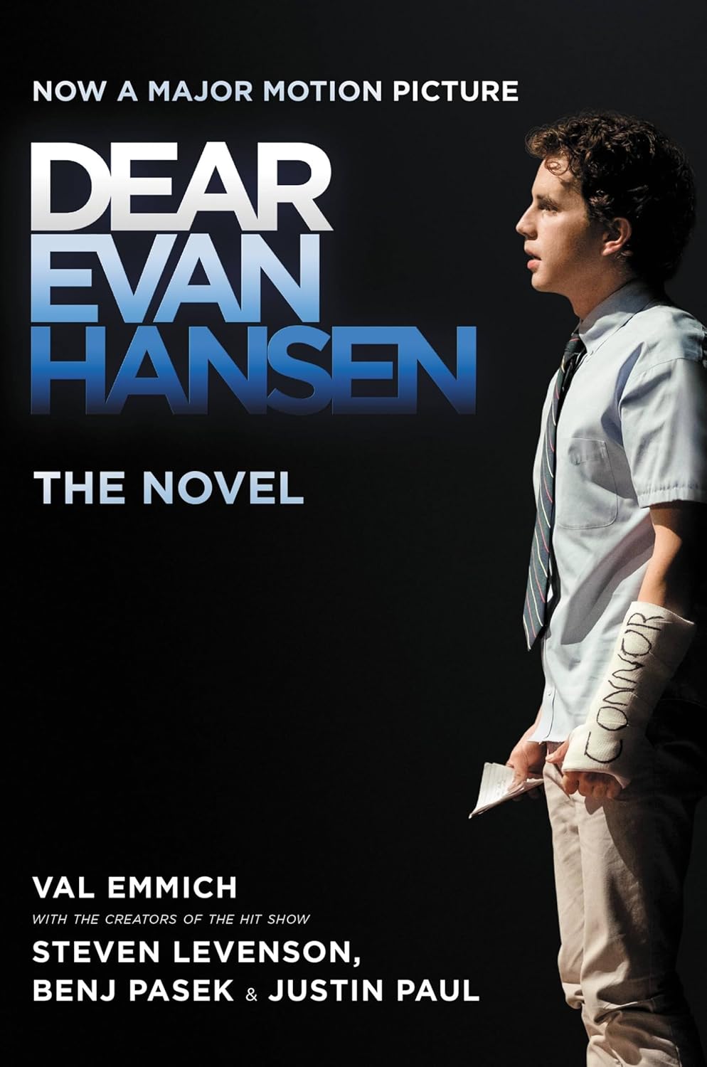 Book cover of 'Dear Evan Hansen' with a person holding a script against a dark background.